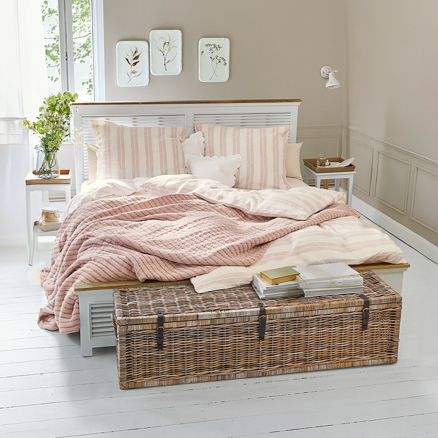 Letto Antje Camera accogliente con letto a righe rosa chiaro e baule in vimini su pavimento bianco