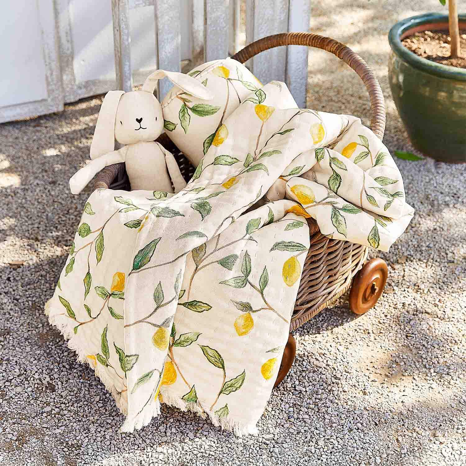 Cesto in vimini su ruote con coperta in cotone crema a motivo limoni e peluche coniglio