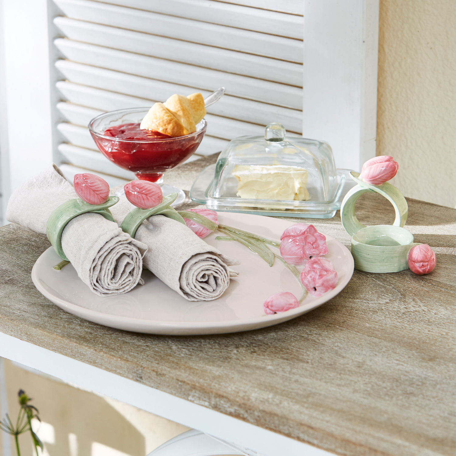 Set di 4 portatovaglioli ad anello Monique Anelli portatovaglioli in ceramica con fiori rosa su piatto beige su tavolo in legno