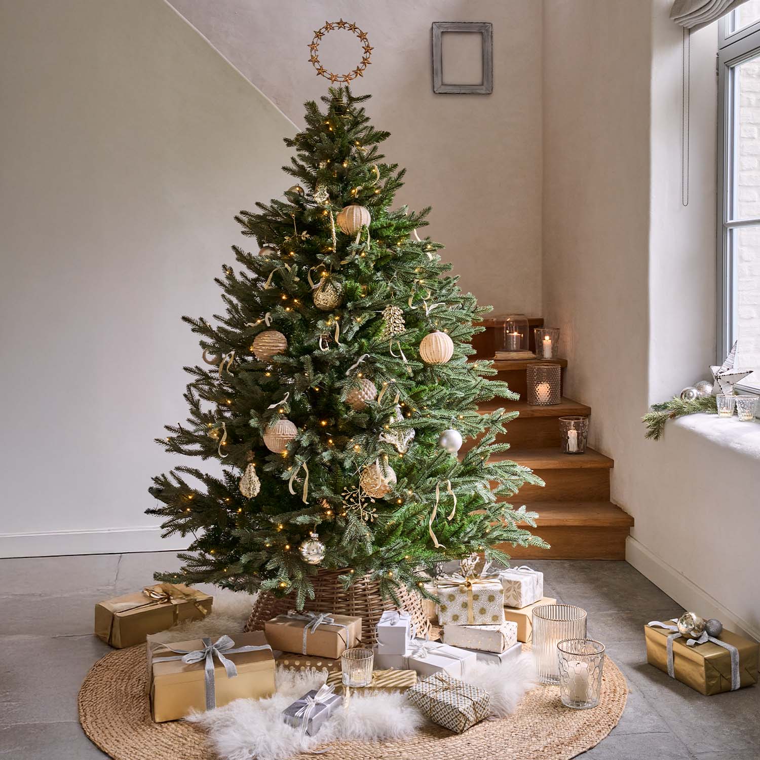Albero di Natale verde con decorazioni naturali e regali dorati su tappeto rotondo in stanza luminosa