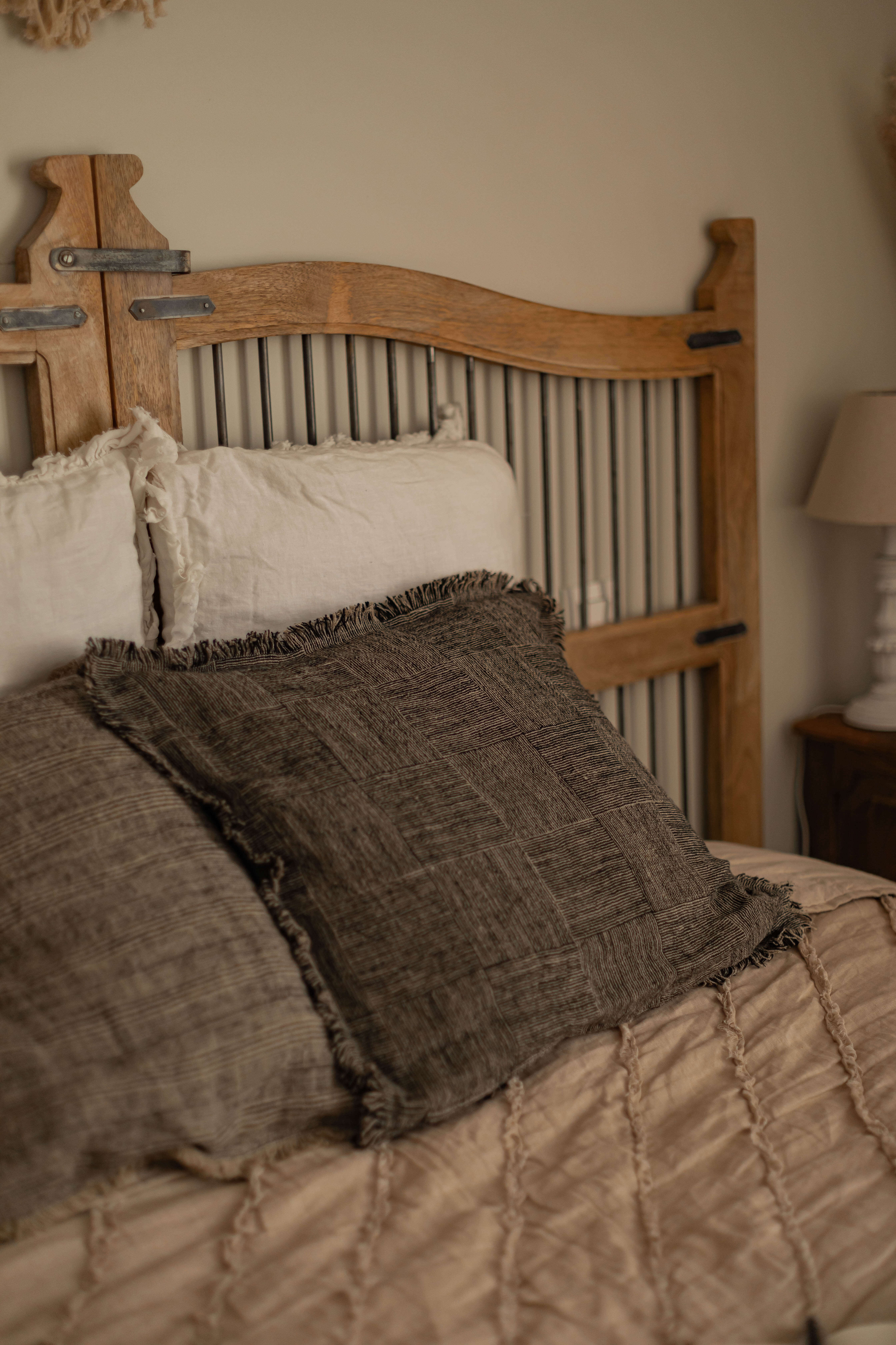 Camera da letto con testiera in legno e cuscini beige e marroni sul letto