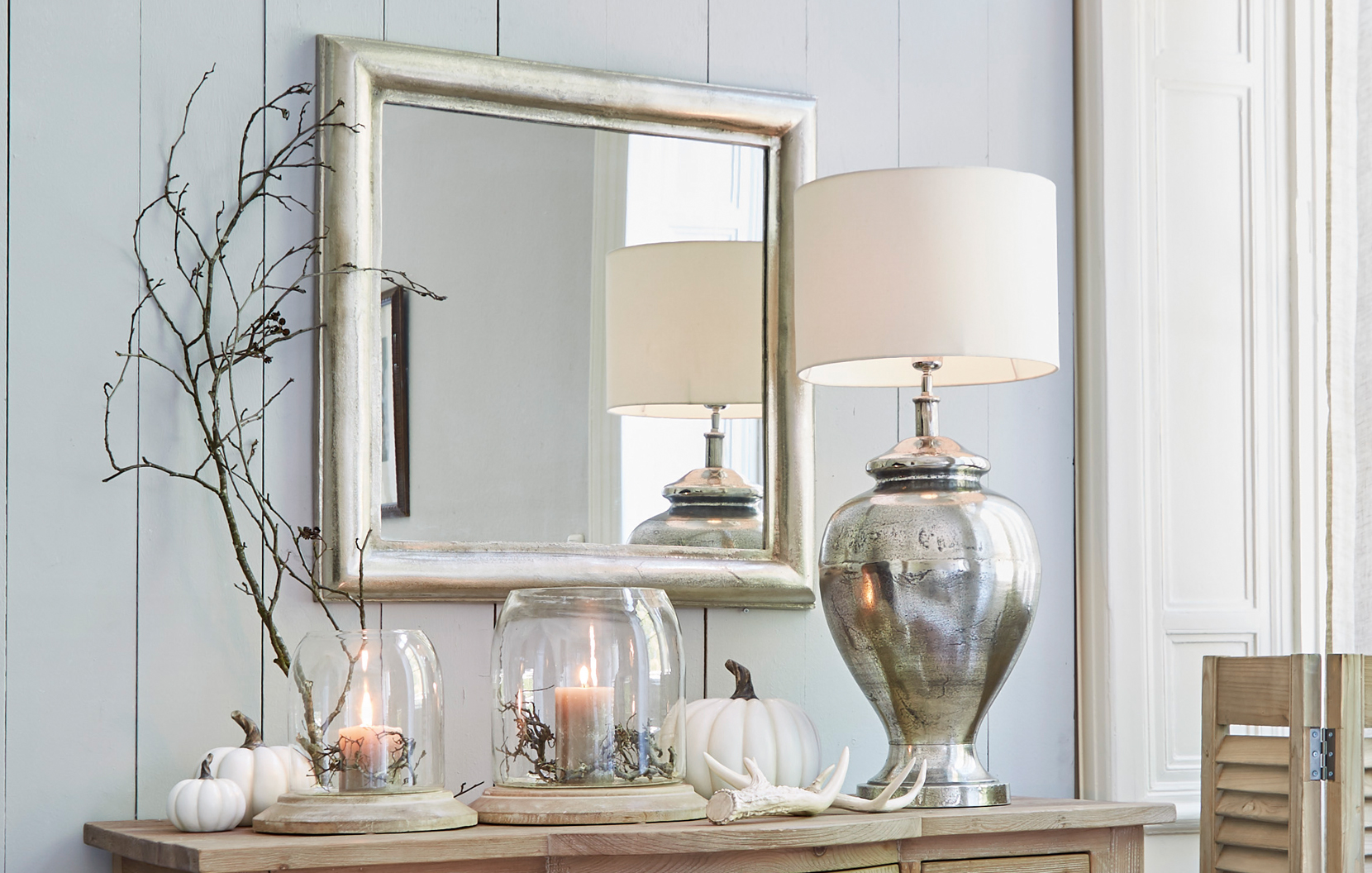 Interno classico elegante con specchio argentato, lampada in metallo e decorazioni su mobile in legno