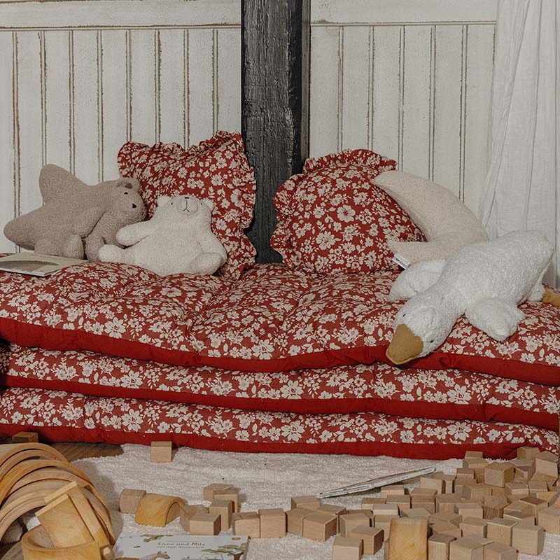 Cuscini e materassi rossi a fiori con peluche in angolo giochi per bambini con blocchi di legno