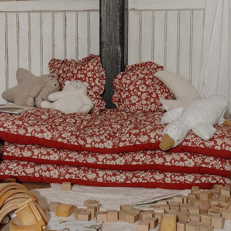 Cuscini e materassi rossi a fiori con peluche in angolo giochi per bambini con blocchi di legno