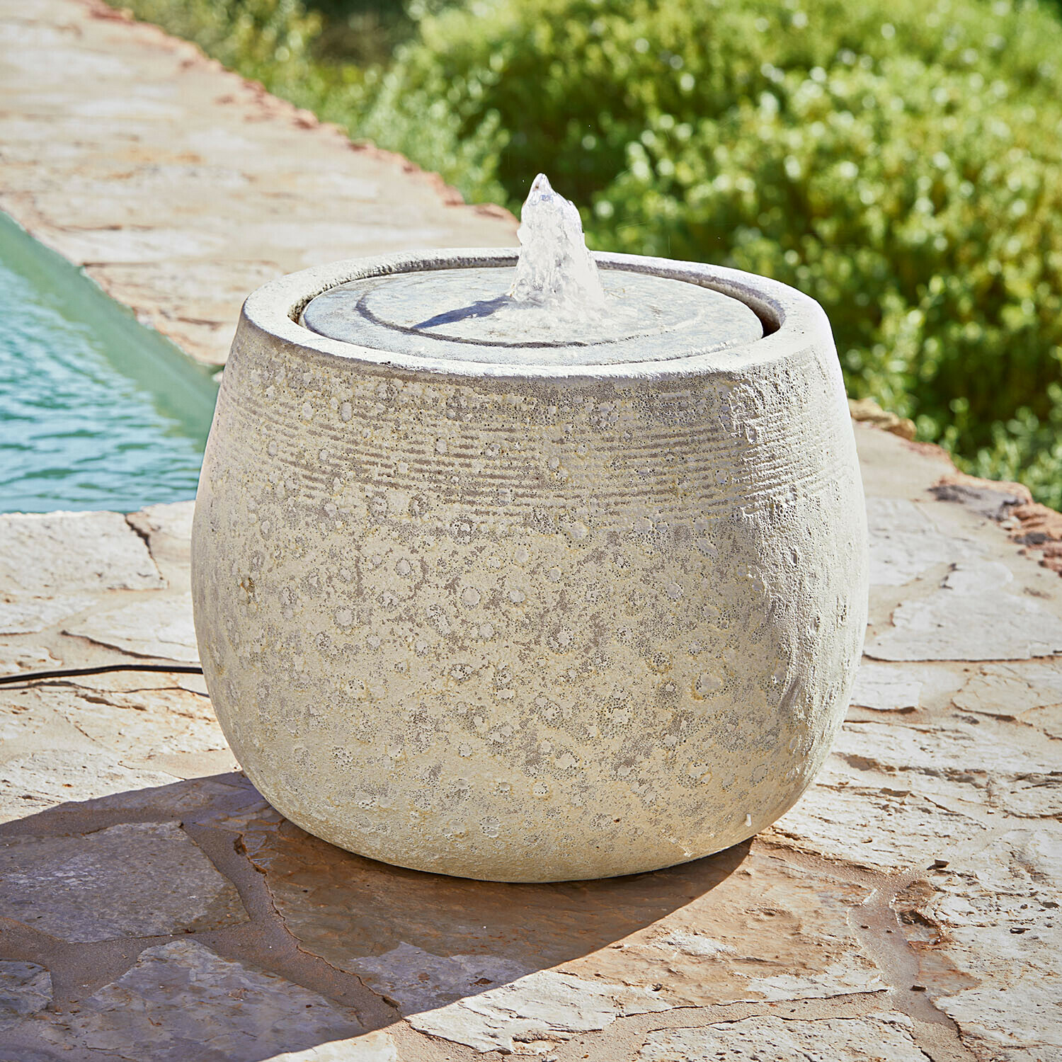Fontana Seravia Fontana da giardino rotonda in pietra chiara con motivo delicato e getto d'acqua su terrazza in pietra