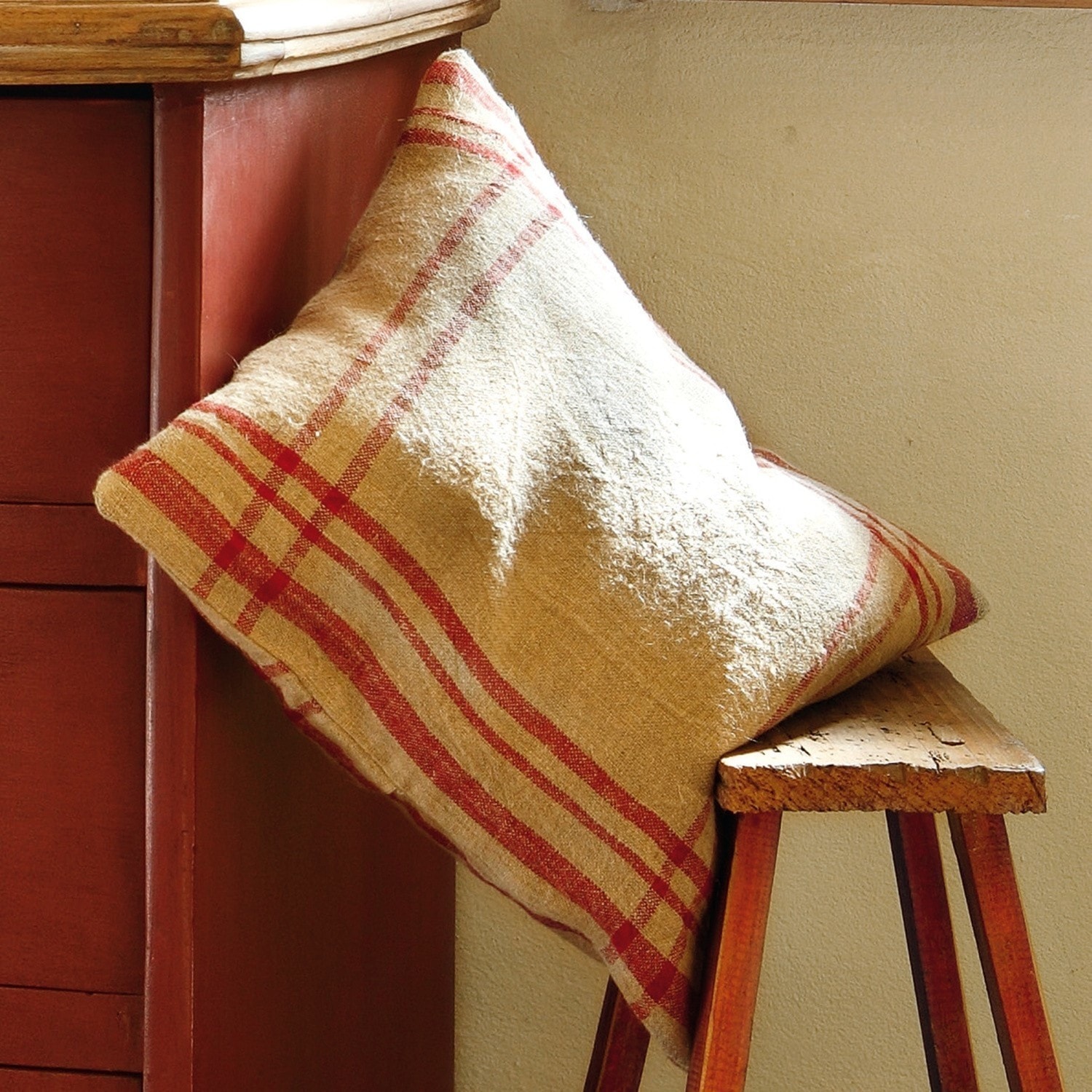 Copricuscino Damian Cuscino beige con motivo a quadri rossi su panca in legno, decorazione per interni