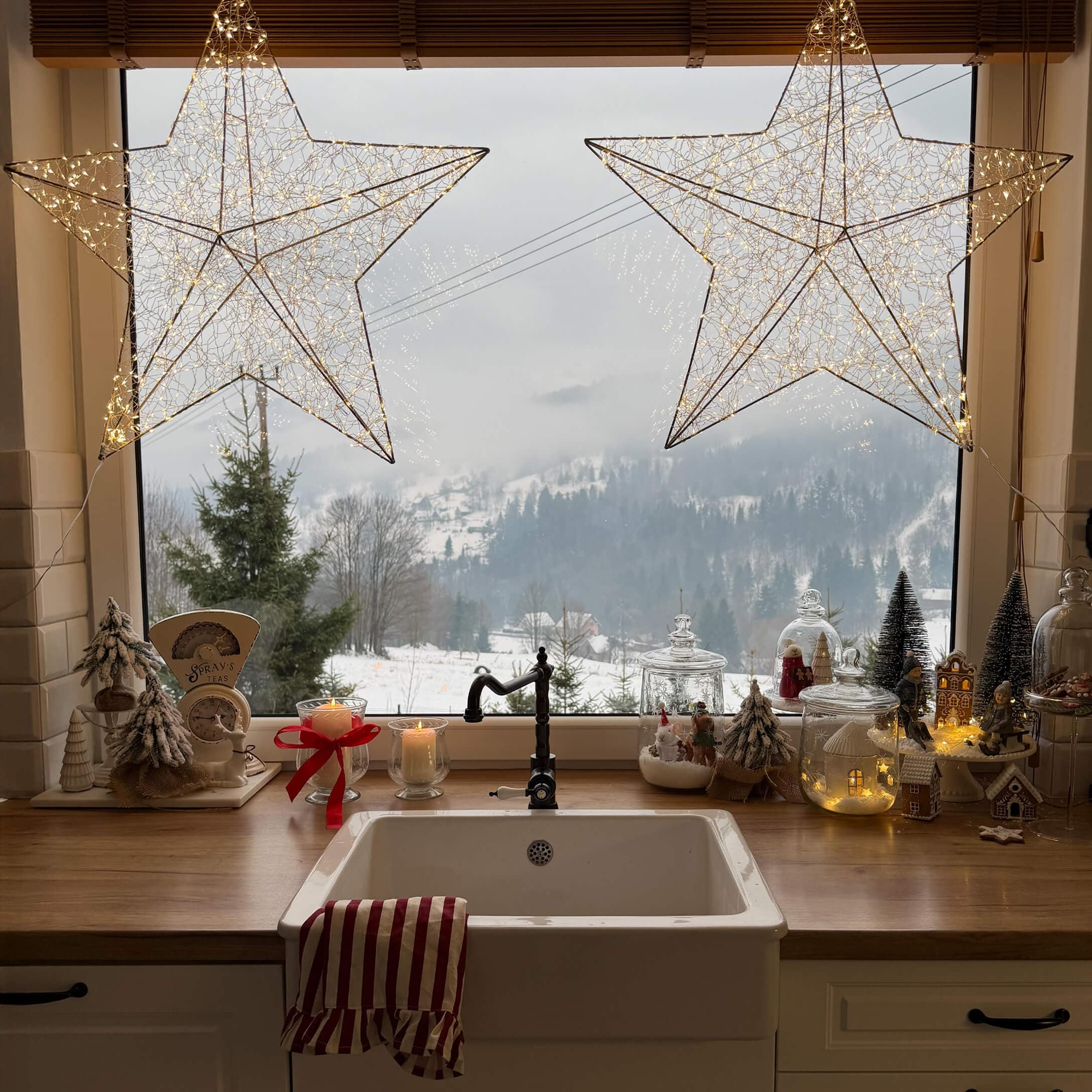 Cucina con lavello bianco, piano in legno, decorazioni natalizie e vista su paesaggio invernale