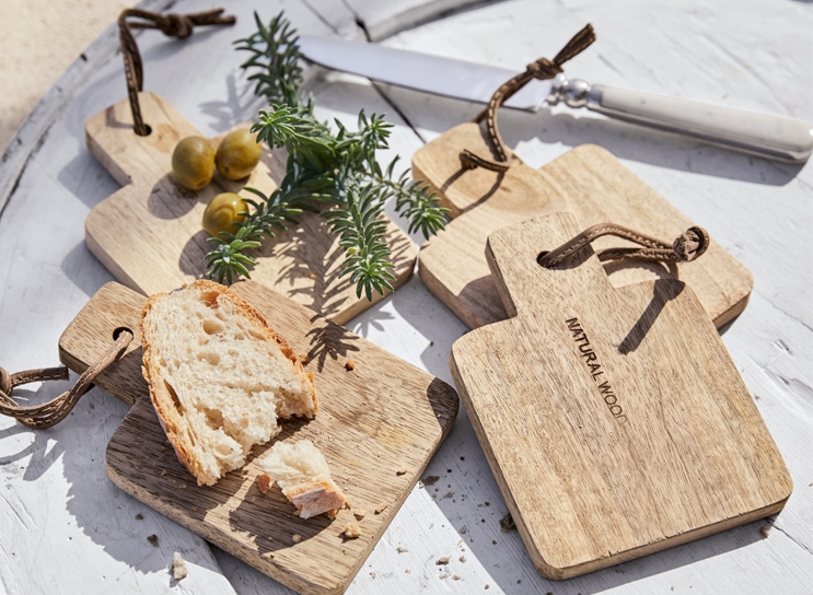 Set di taglieri in legno naturale con pane e olive su tavolo bianco in stile mediterraneo