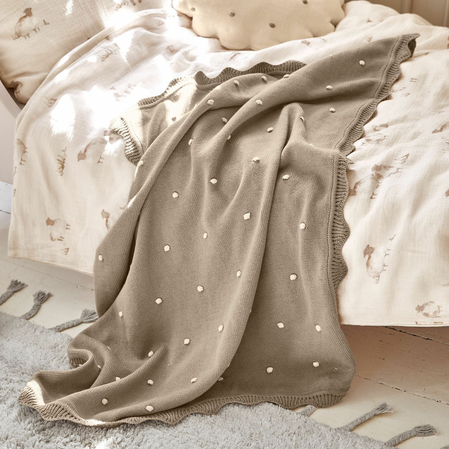 Plaid Saphie Coperta beige lavorata a maglia con pois bianchi su letto chiaro, soffice e decorativa
