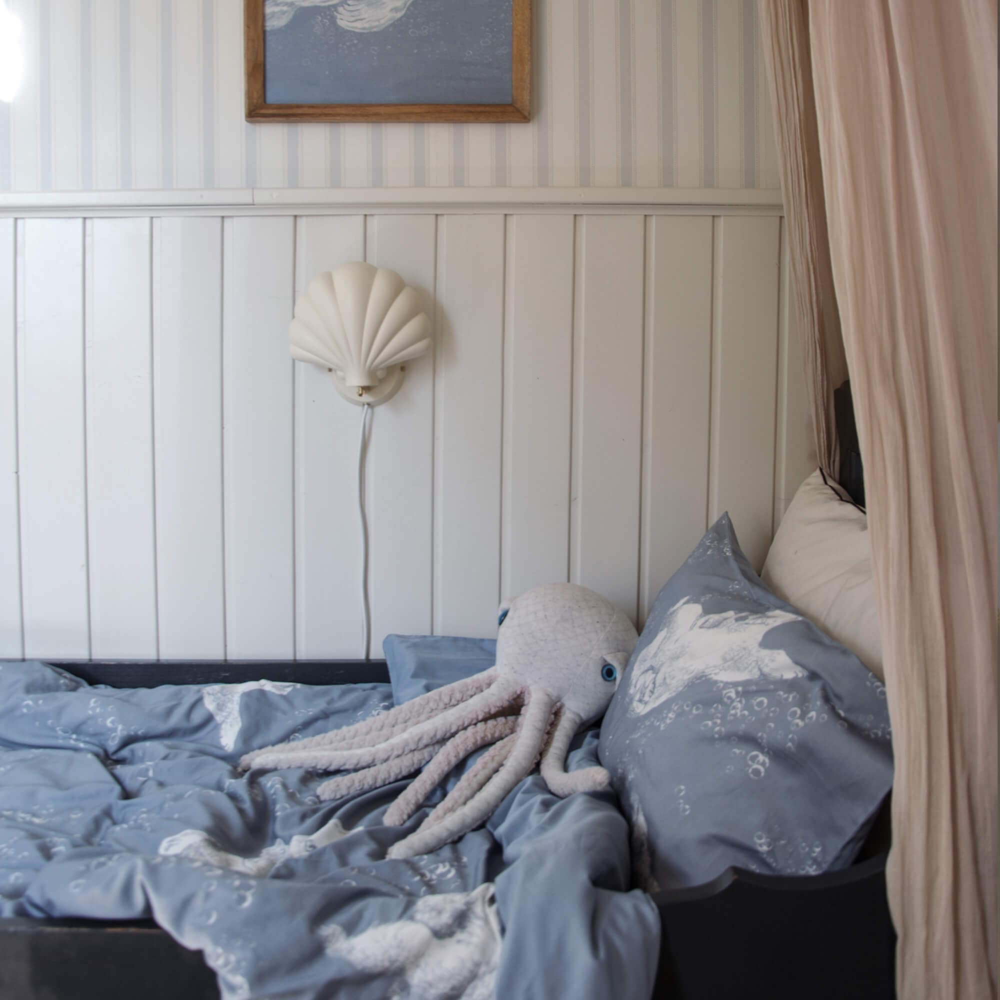 Biancheria da letto per bambini blu con motivo marino e polpo di peluche su un letto in camera bambini