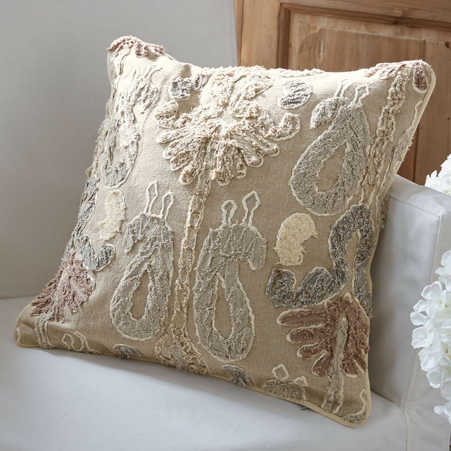Copricuscino Rahmira Cuscino decorativo beige con motivo ricamato in colori naturali su divano bianco