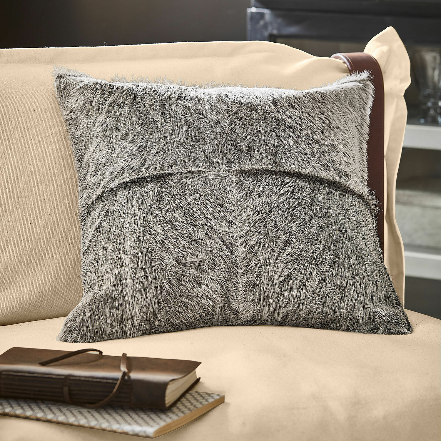 Copricuscino Nymarion Cuscino decorativo grigio in materiale peloso su divano beige, accessorio elegante per interni