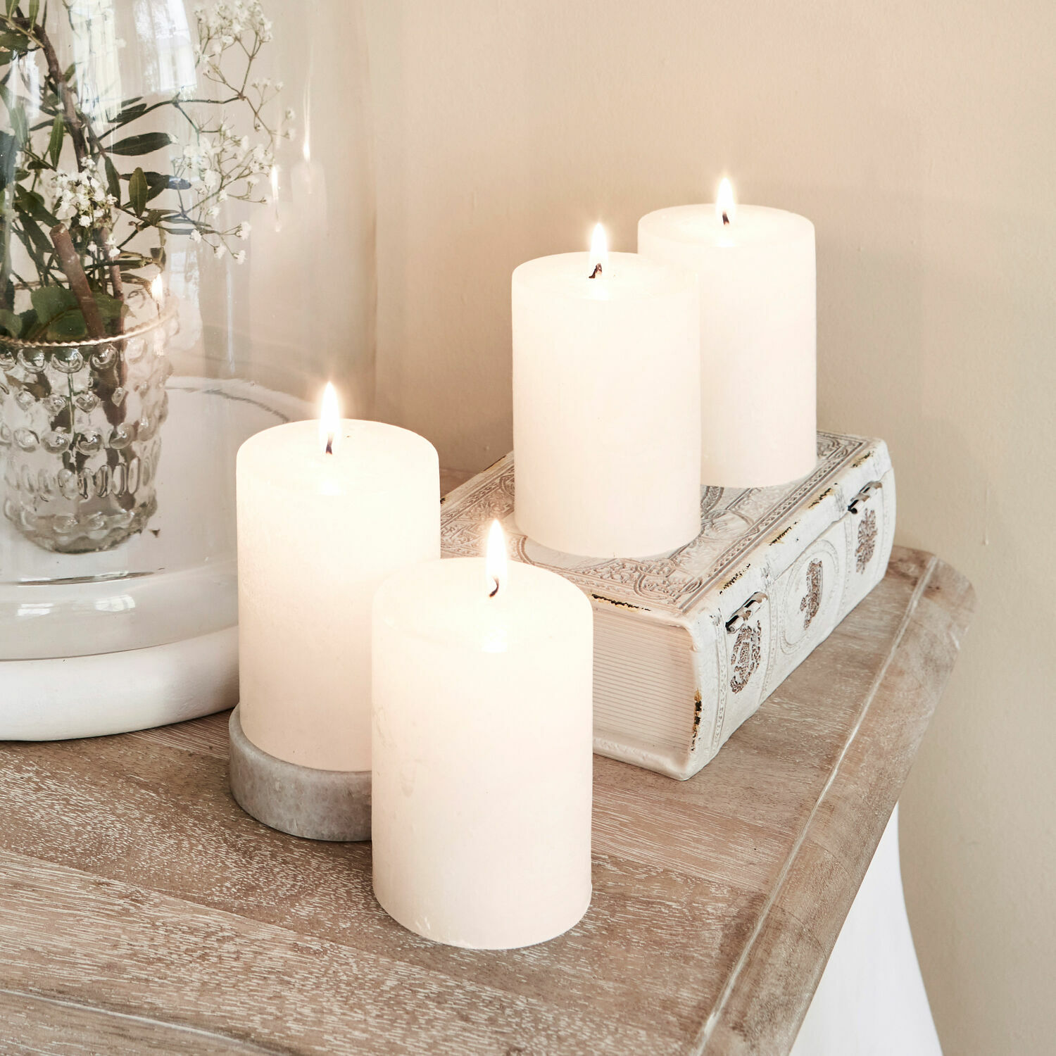 Set di 4 candele Virrans Quattro candele bianche decorative su tavolo in legno con libro decorativo e vaso di vetro