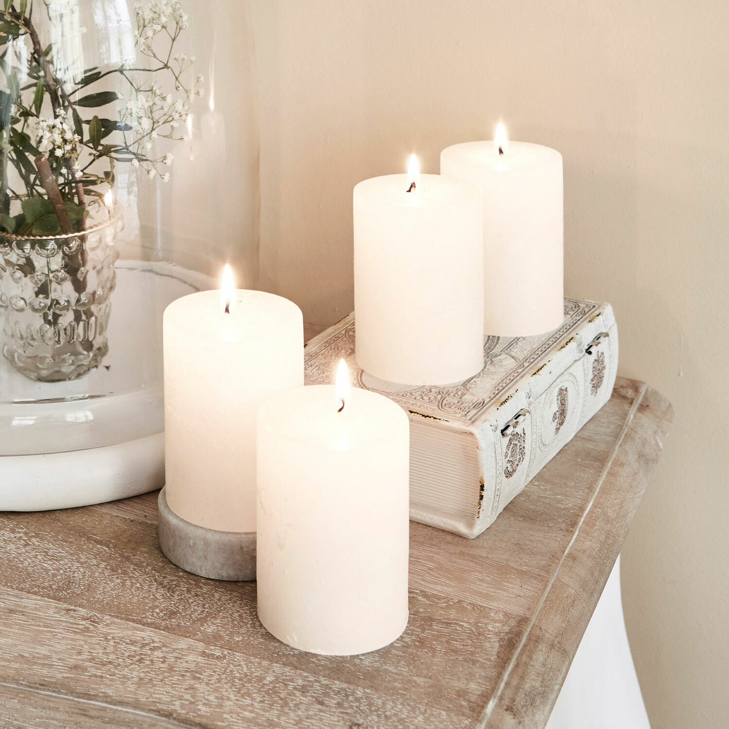 Set di 4 candele Virrans Quattro candele bianche decorative su tavolo in legno con libro decorativo e vaso di vetro