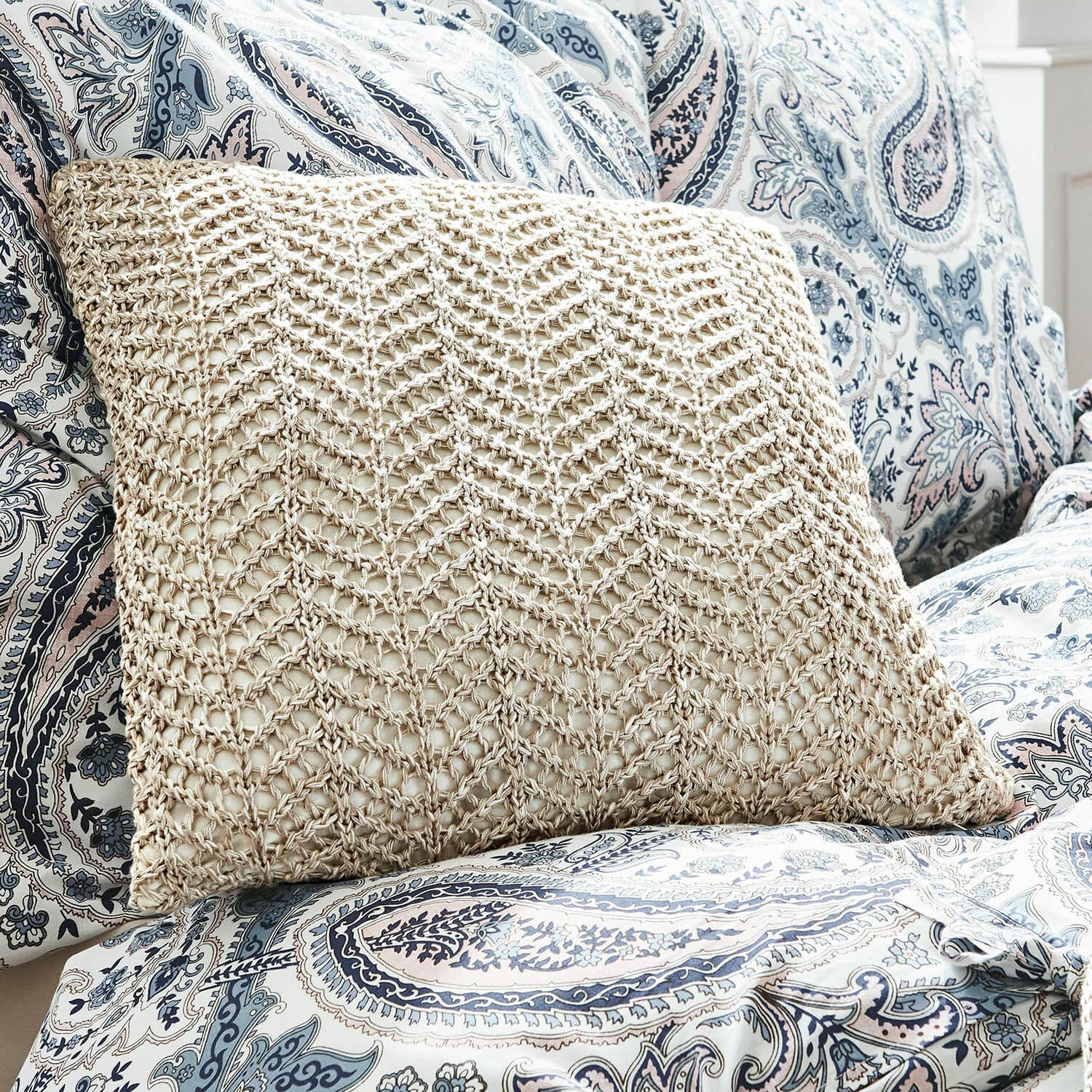 Copricuscino Lukretia Cuscino beige con motivo intrecciato su copertura blu e bianca con fantasia paisley
