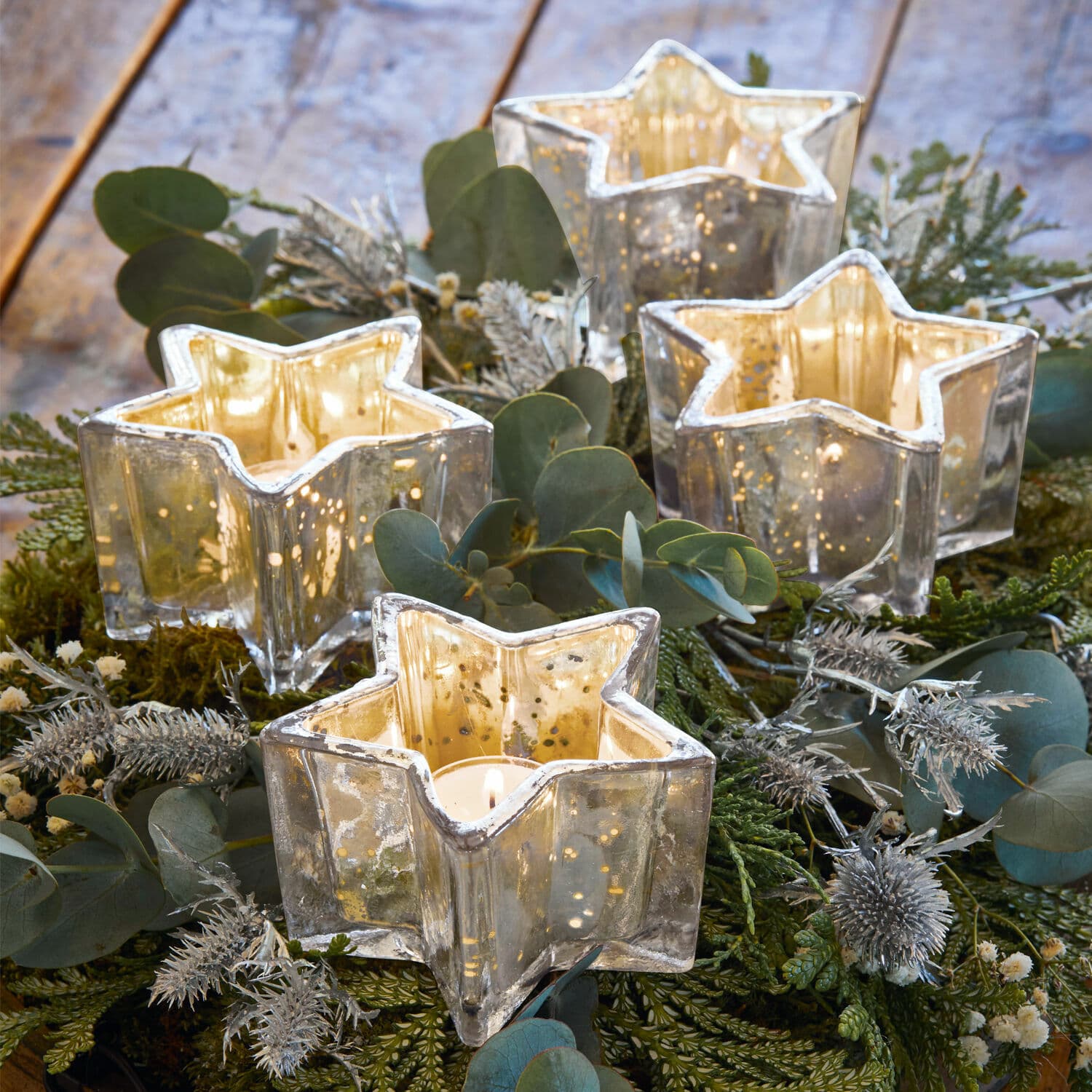 Set di 4 portacandeline con supporto Bernice Portacandele in vetro a forma di stella con effetto specchio argentato su sfondo decorativo verde