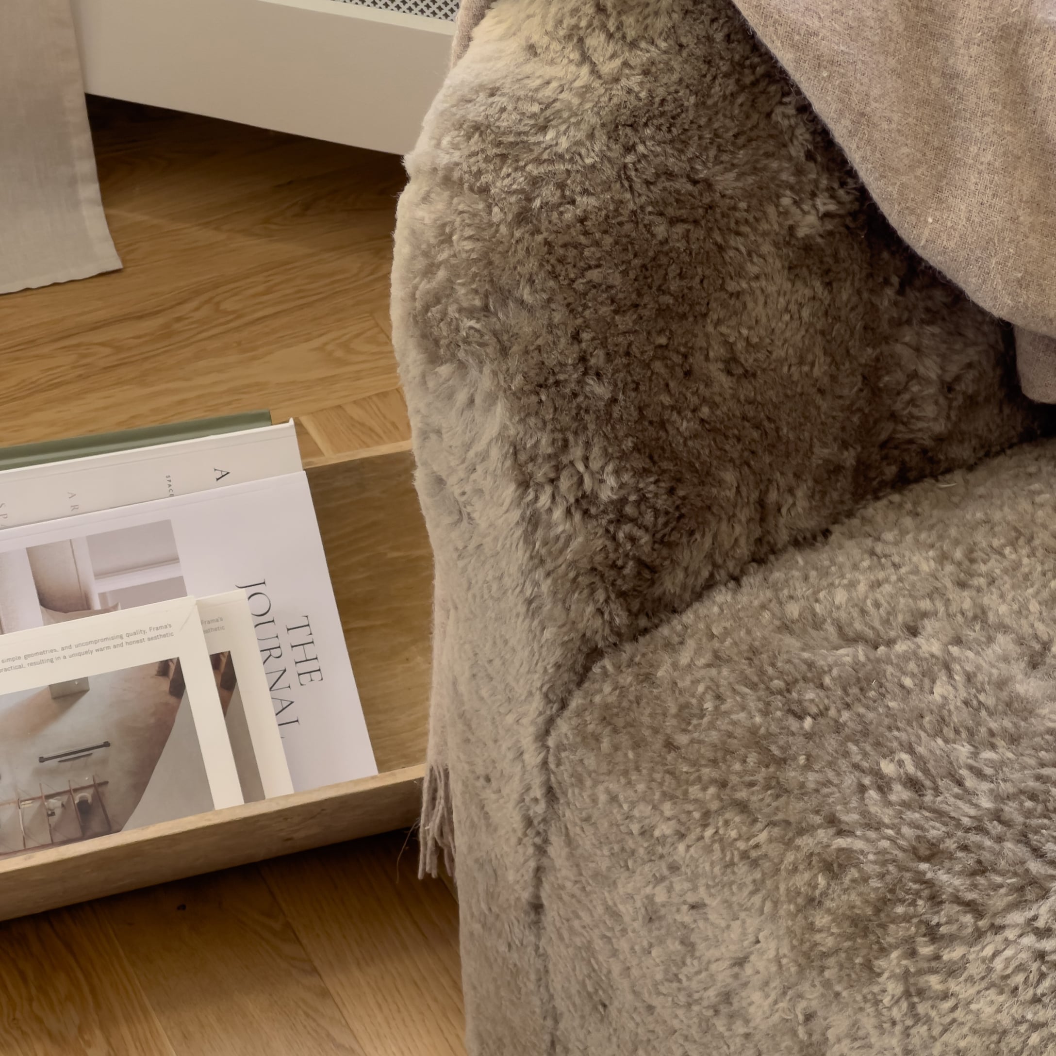 Angolo invernale accogliente con materiale peloso beige e pavimento in legno chiaro