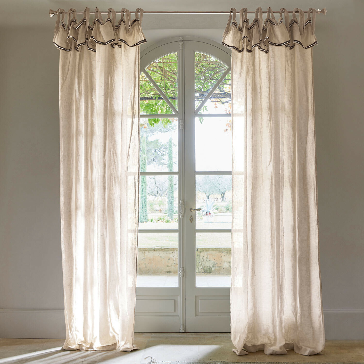 Tenda Romagny Tende in lino beige con bordo decorativo appese a finestra con vista sul giardino, decorazione casa