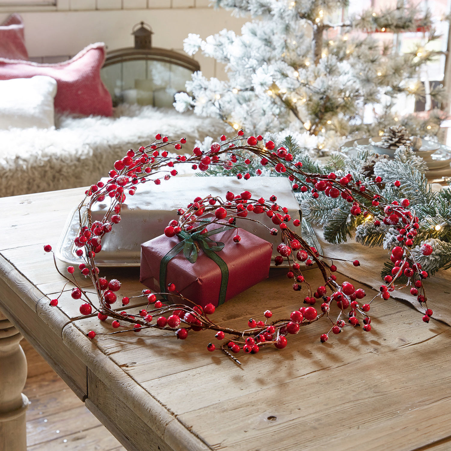 Ghirlanda Rimont Corona decorativa di bacche rosse su tavolo in legno con regalo e decorazioni natalizie