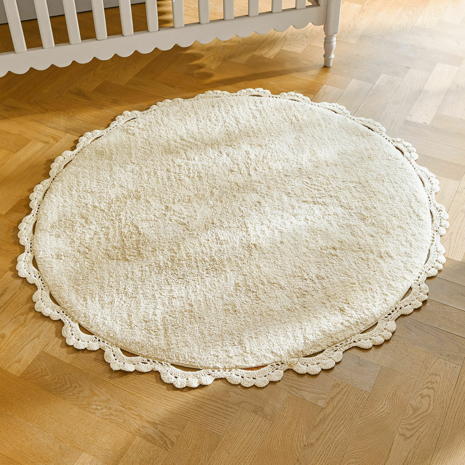Tappeto Arash Tappeto rotondo crema in cotone con bordo in pizzo su pavimento in legno chiaro, decorazione d'interni