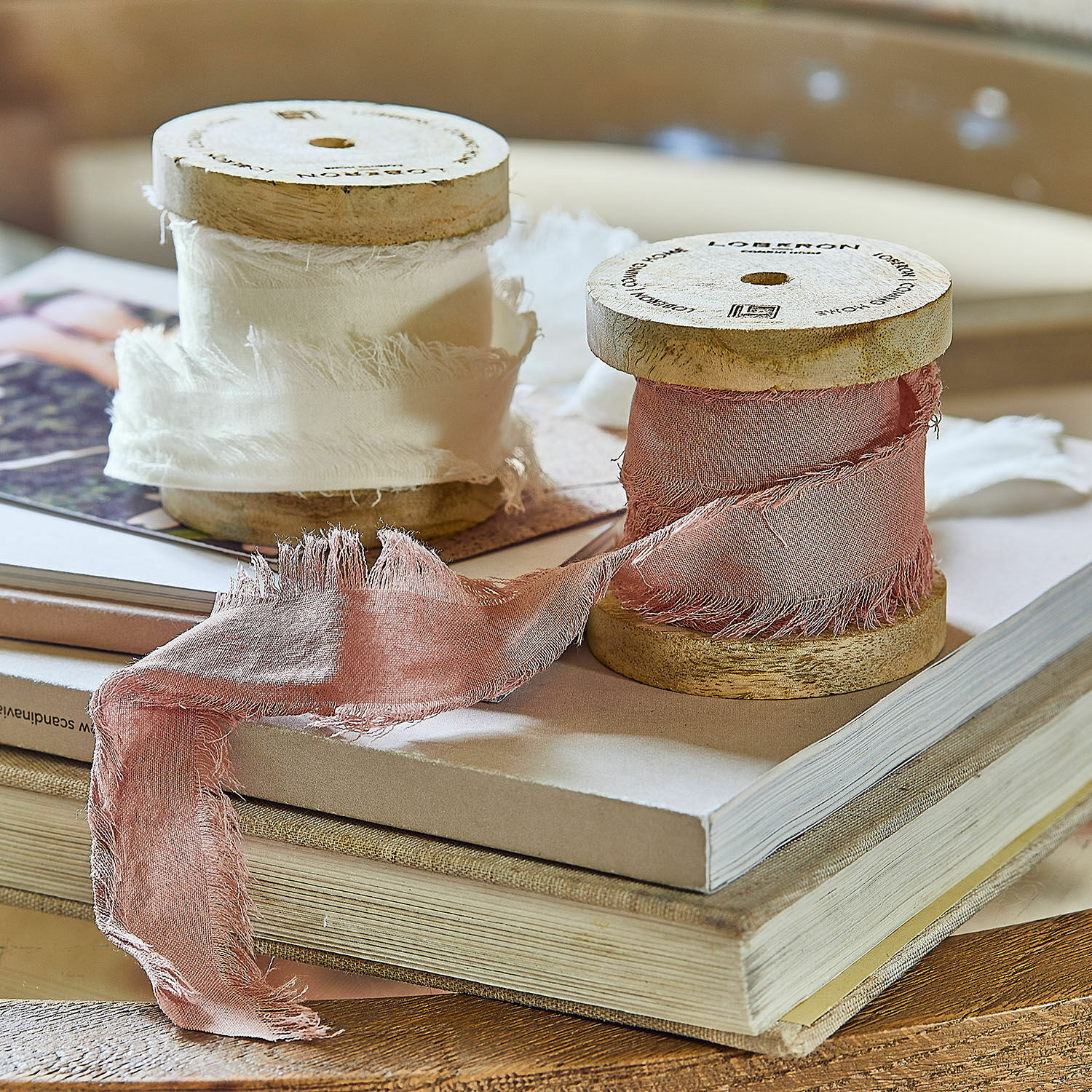 Coppia di nastri Valethor Bobine in legno con nastro di cotone bianco e rosa su pila di libri, decorazione per interni