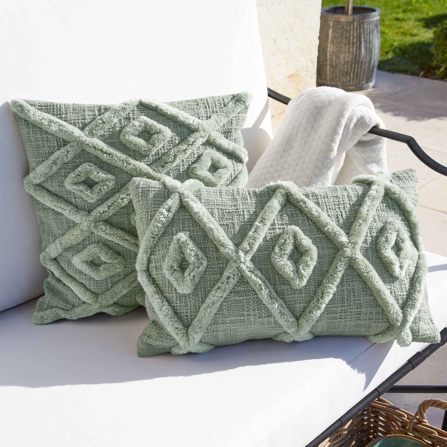 Morbido cuscino decorativo verde con motivo geometrico su sedia da giardino bianca