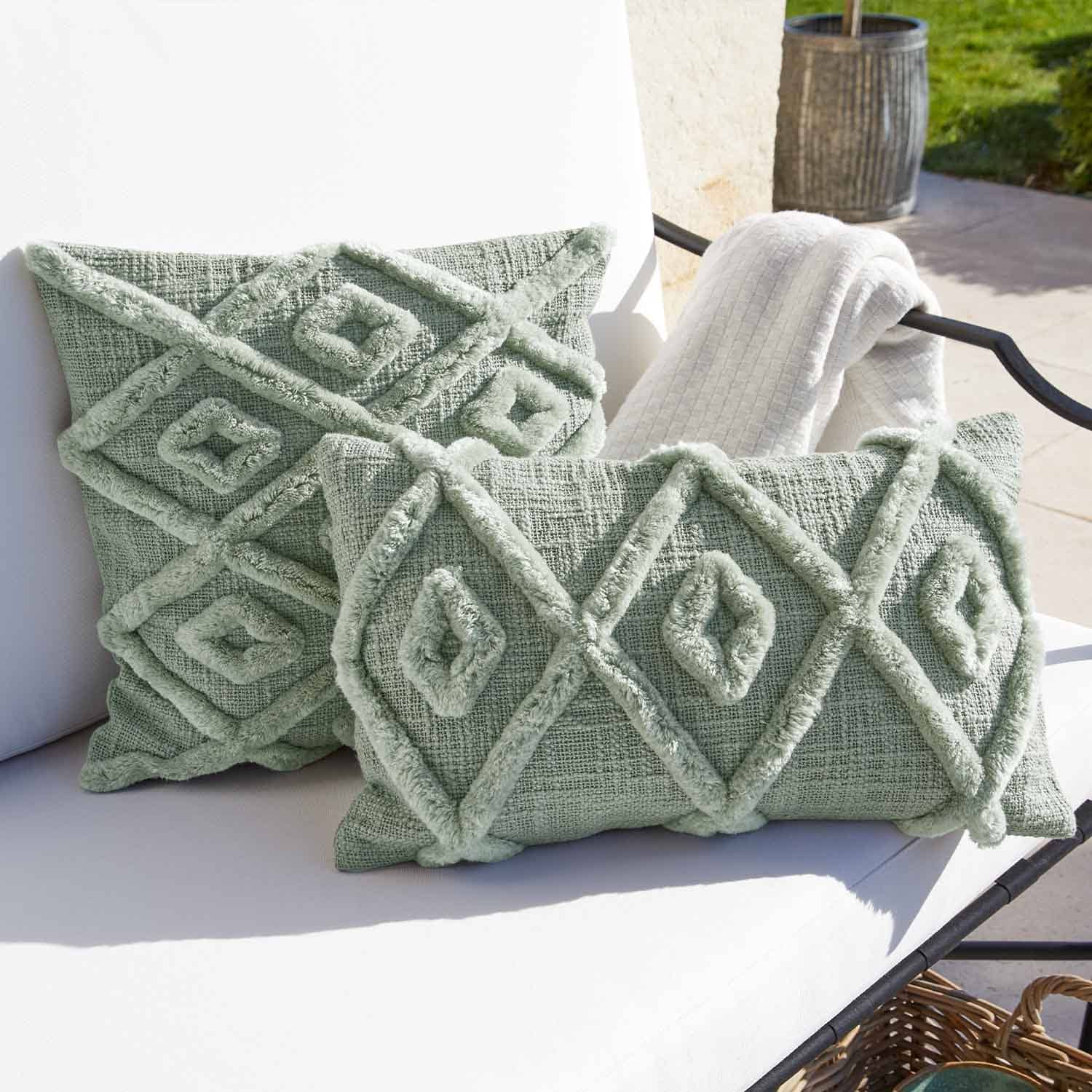 Morbido cuscino decorativo verde con motivo geometrico su sedia da giardino bianca