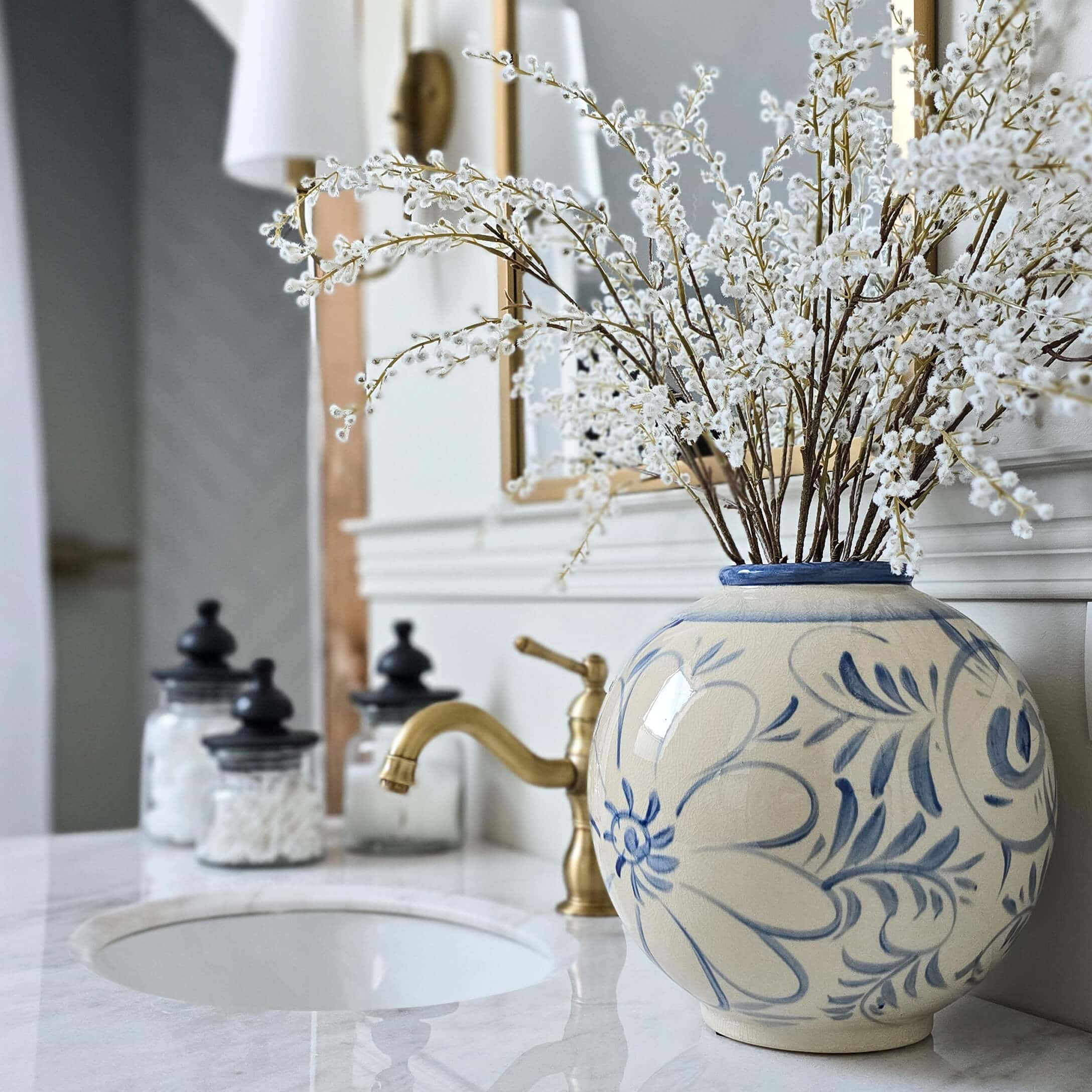 Vaso rotondo in ceramica con motivo floreale blu su piano bagno in marmo con decorazioni