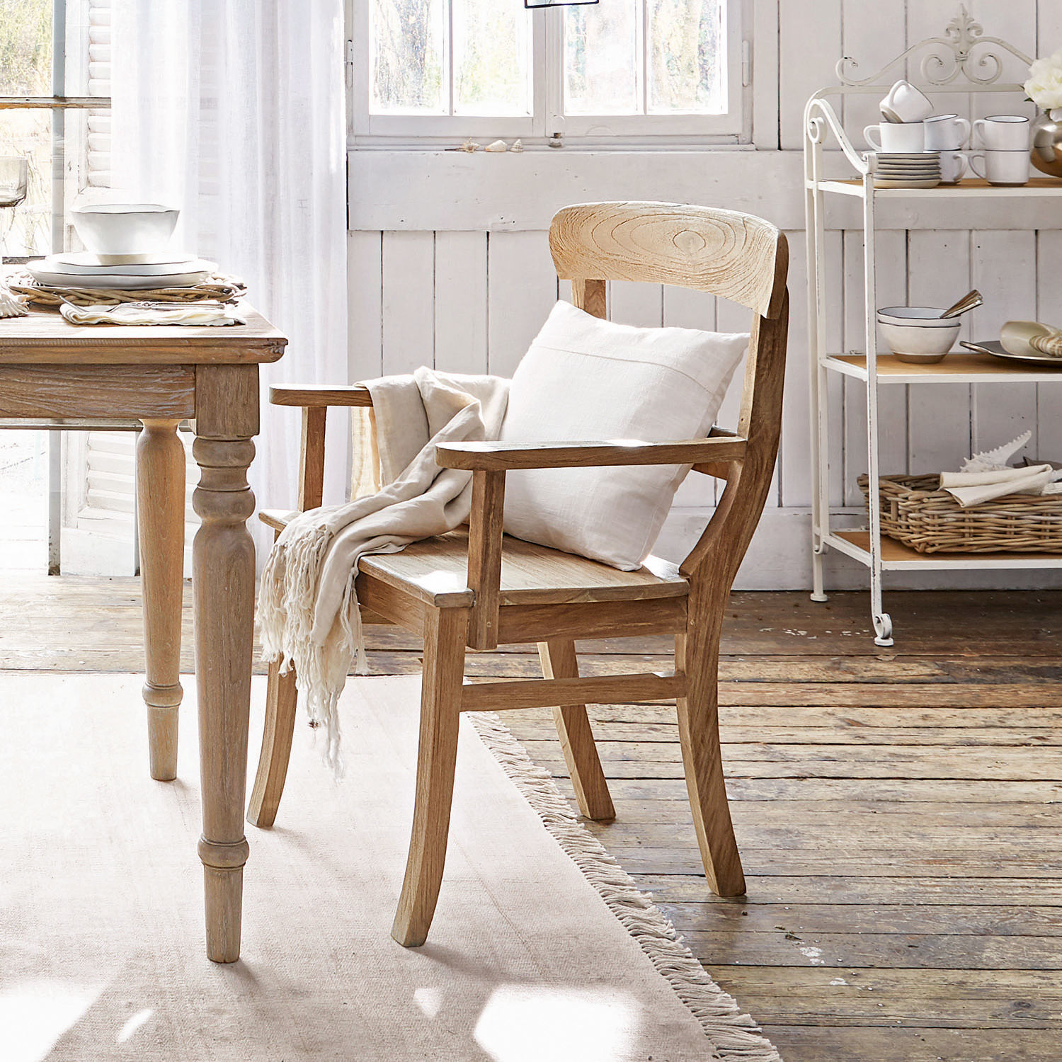 Sedia con braccioli Masters Sedia in legno chiaro con braccioli, cuscino bianco e coperta in un interno accogliente e luminoso