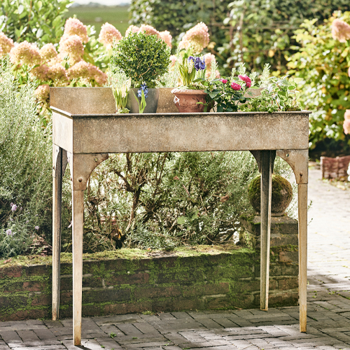 Tavolo da giardino in metallo beige con fiori, ideale per coltivare piante all'aperto