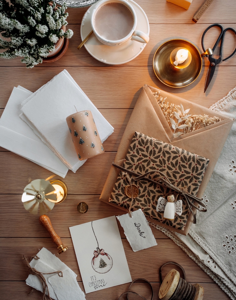 Set per confezionare regali con carta naturale, candela e biglietto di Natale su tavolo in legno