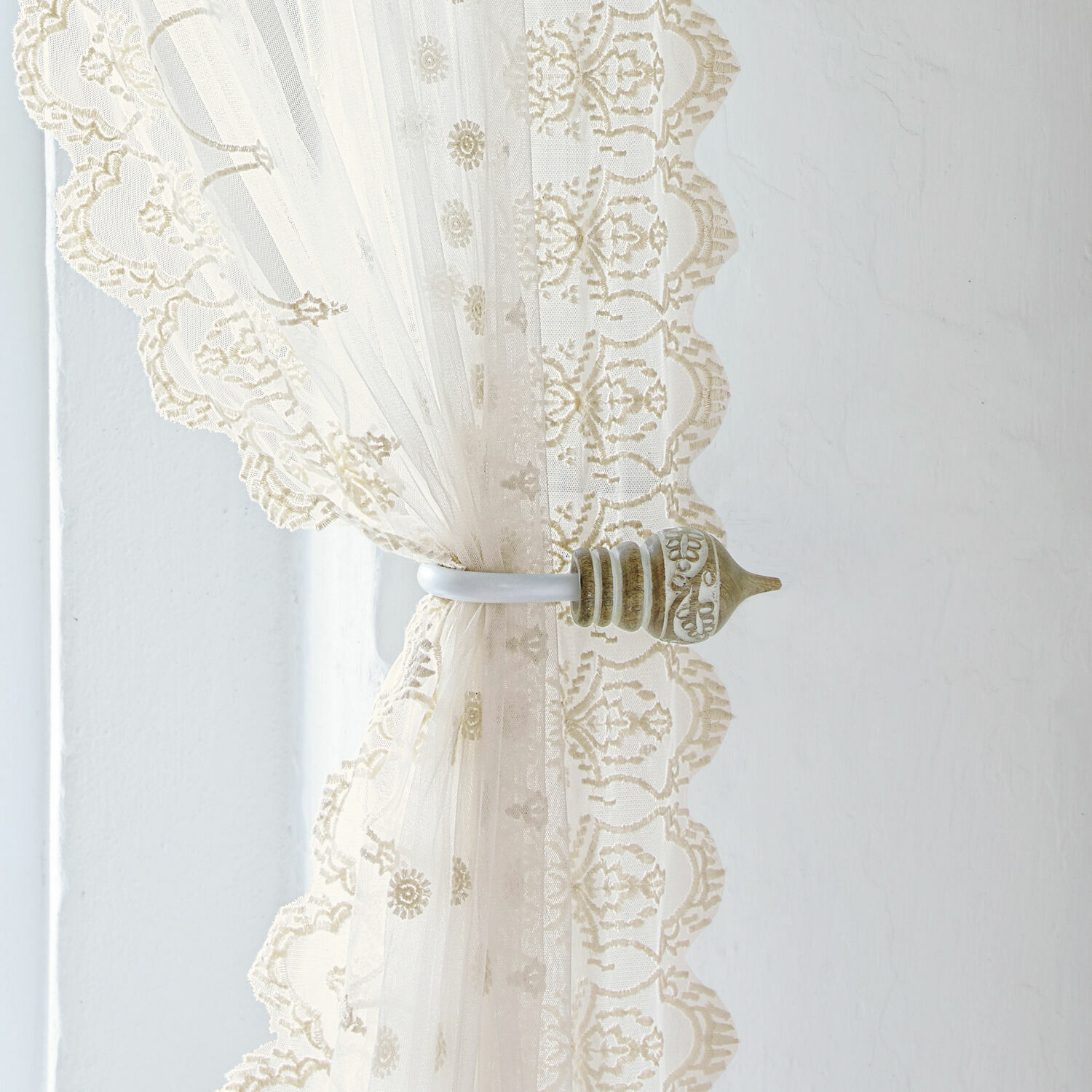 Coppia di fermatenda Talon Tenda in pizzo beige con supporto decorativo in metallo su sfondo di parete chiara, decorazione finestra