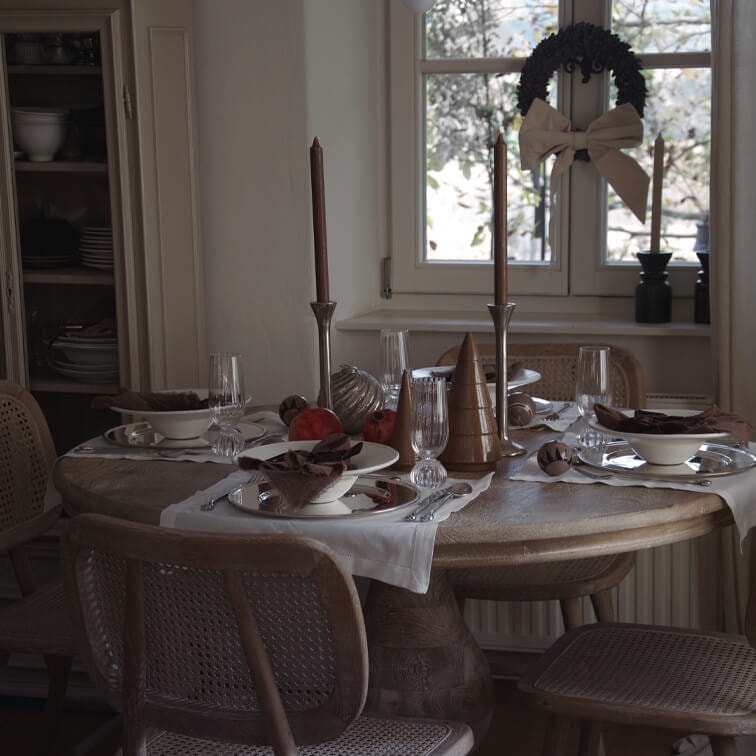 Tavolo rustico in legno con decorazioni natalizie e candele marroni in una sala da pranzo accogliente