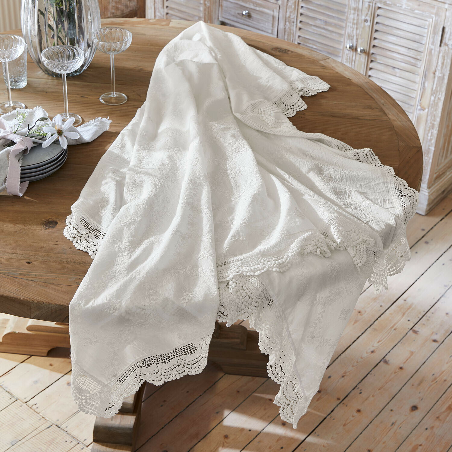 Tovaglia bianca con bordo in pizzo su tavolo in legno, decorazione elegante per sala da pranzo