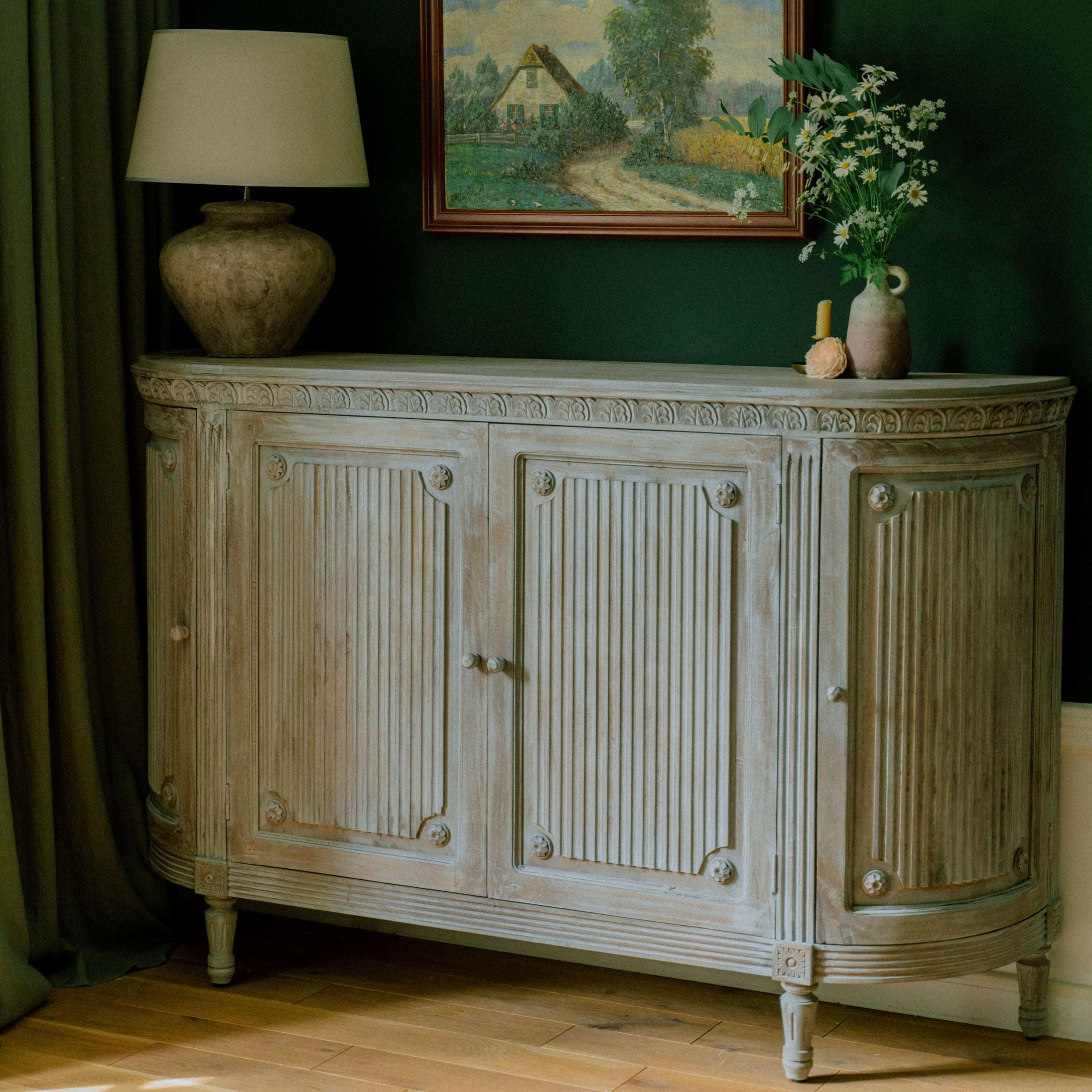 Credenza in legno chiaro con dettagli intagliati e decorazioni floreali in ambiente elegante