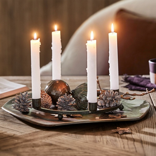 Portacandele decorativo con quattro candele bianche e pigne naturali su tavolo in legno