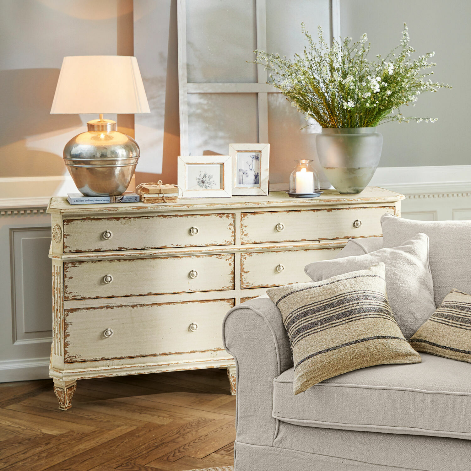 Comò Commeren Comò in legno crema stile vintage con lampada, cornici e decorazioni in soggiorno con divano beige