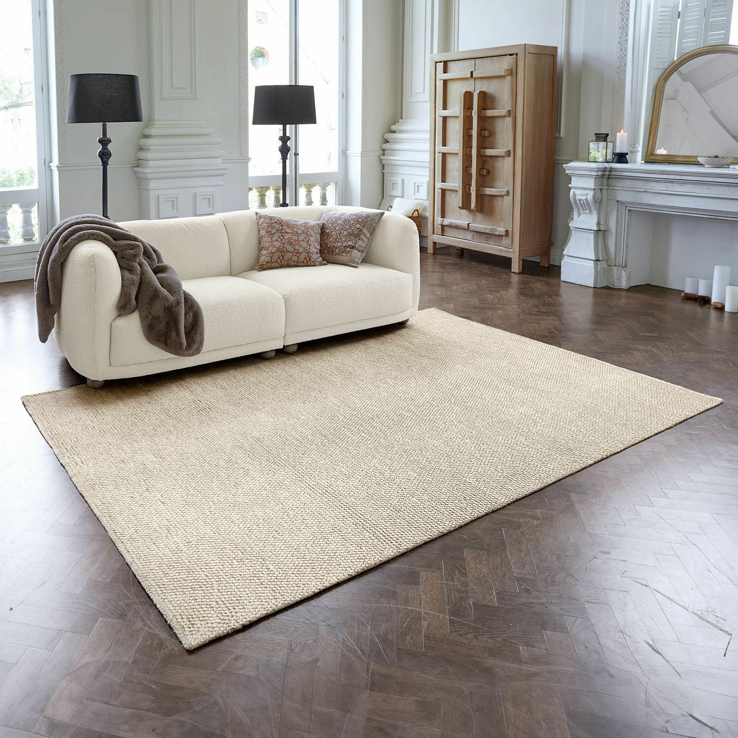 Tappeto Coleman Tappeto beige in materiale naturale su pavimento in legno scuro in soggiorno elegante con divano crema