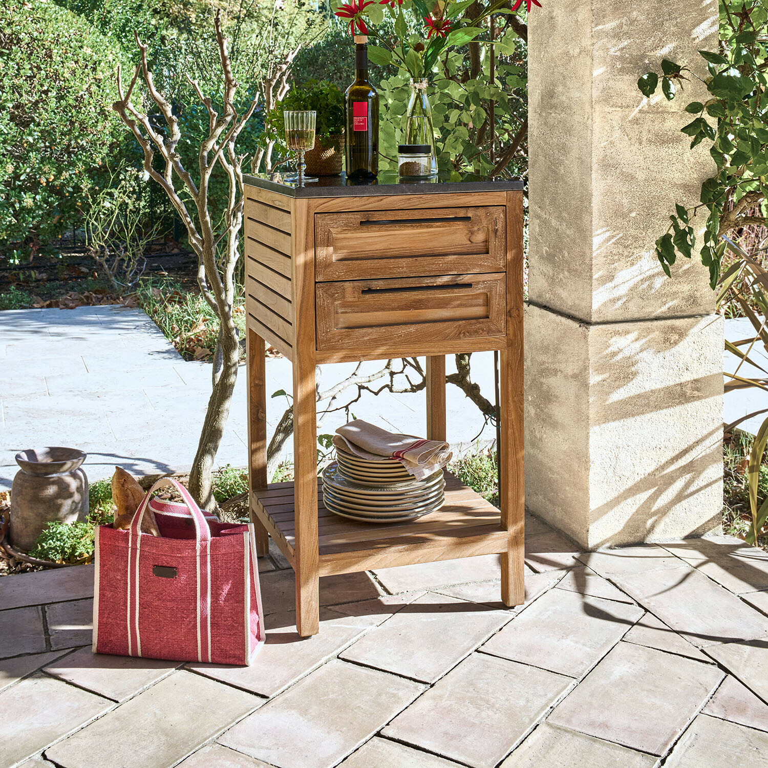 Mobile da cucina per esterni Corviano Mobile in legno con piano nero e due cassetti su terrazza con stoviglie e bottiglia di vino