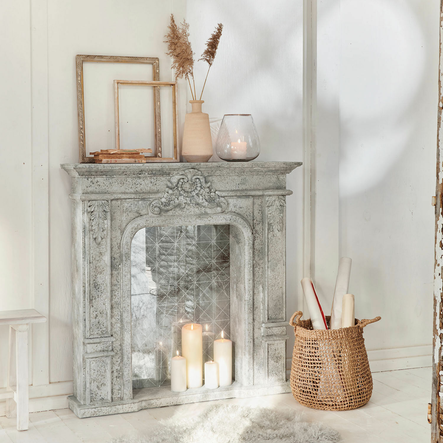 Consolle caminetto Rethonvillers Camino decorativo in pietra grigia con candele accese e cesta di vimini su pavimento bianco