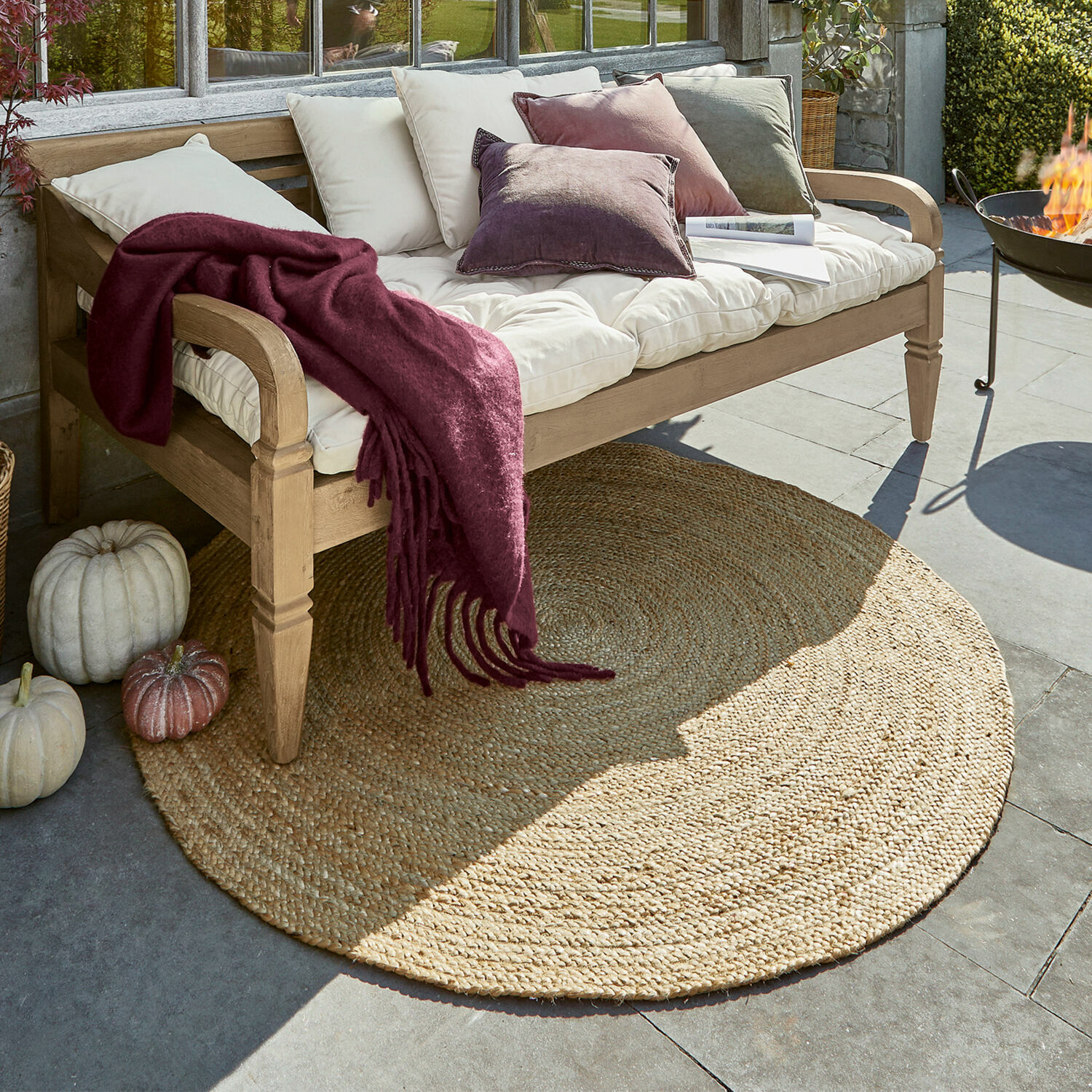 Tappeto Imene Tappeto rotondo in juta colore naturale sotto panca in legno con cuscini e coperta bordeaux