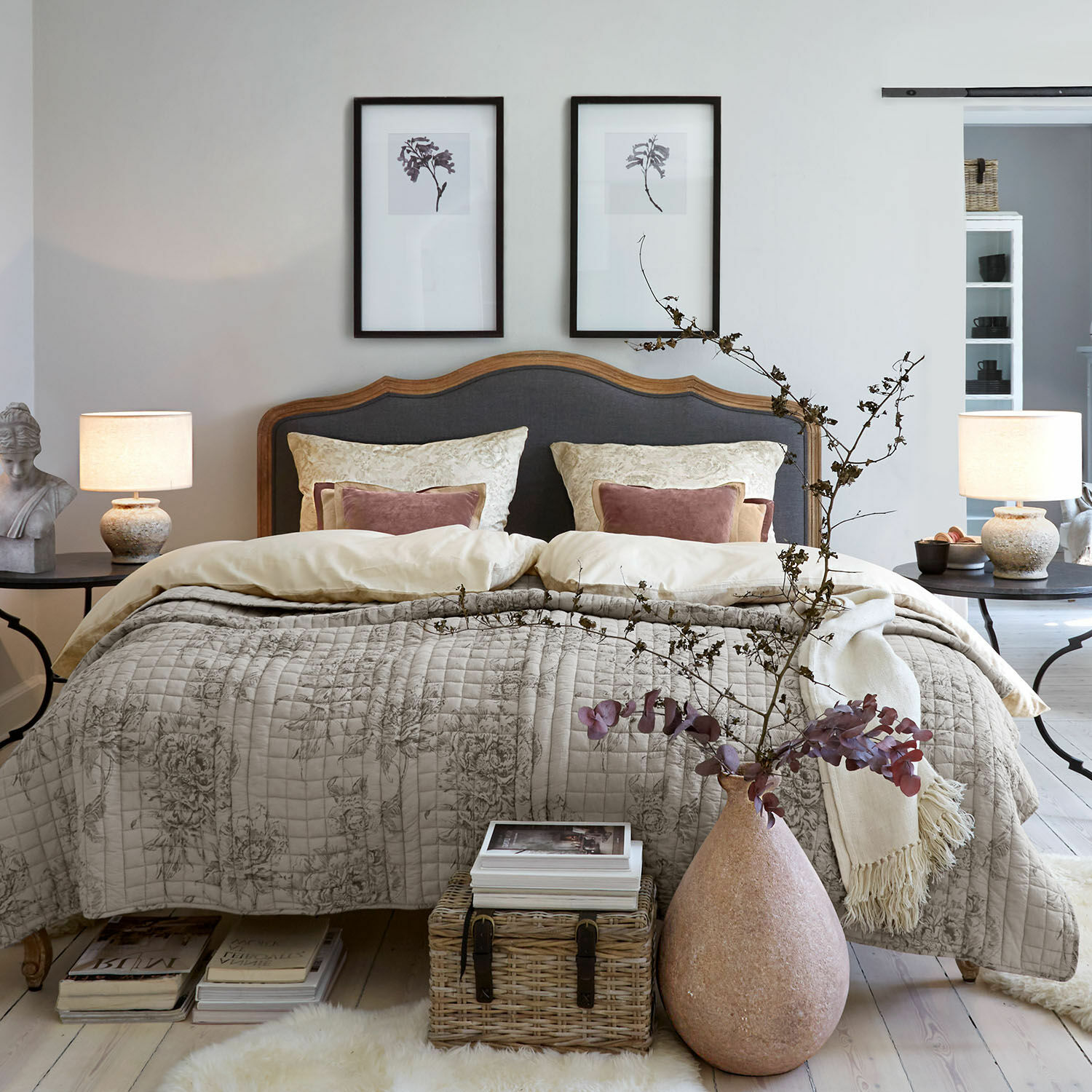 Biancheria da letto Bravonea Camera da letto accogliente con letto in legno e testiera grigia, copriletto beige con motivo floreale, decorazione naturale