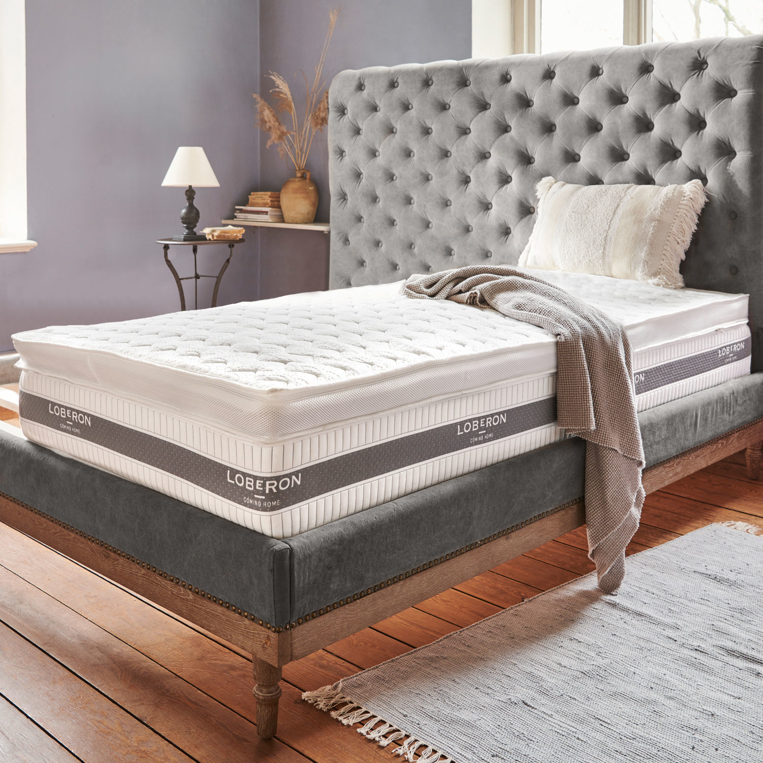 Topper Danisar Letto imbottito grigio con materasso bianco Loberon e coperta beige in camera accogliente