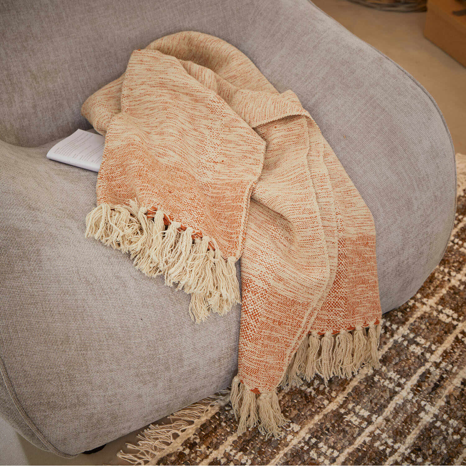 Plaid Winlow Coperta beige e arancione con frange su poltrona grigia, tessuto morbido per decorazione casa