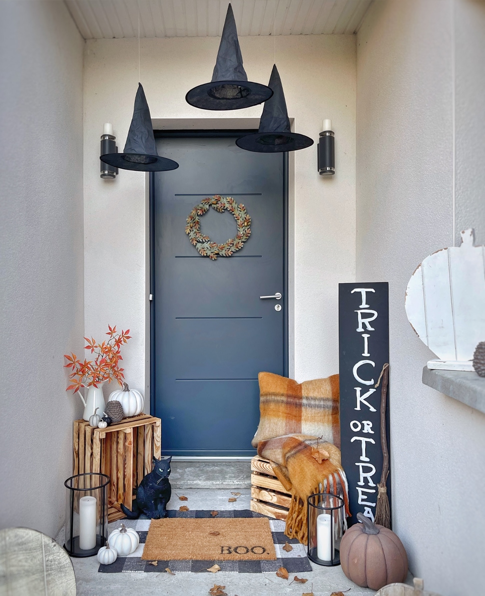 Decorazione di Halloween con cappelli neri, zucche e cartello Trick or Treat su porta blu