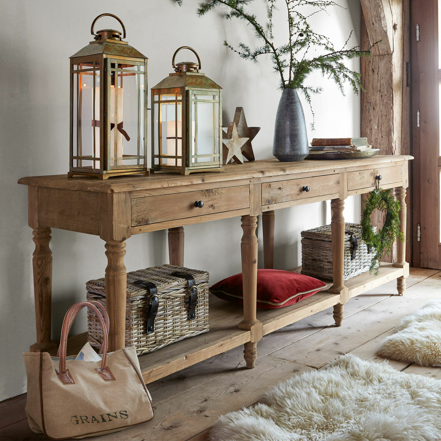 Consolle Misérieux Consolle in legno con tre cassetti, lanterne decorative e cesti di vimini in ambiente accogliente
