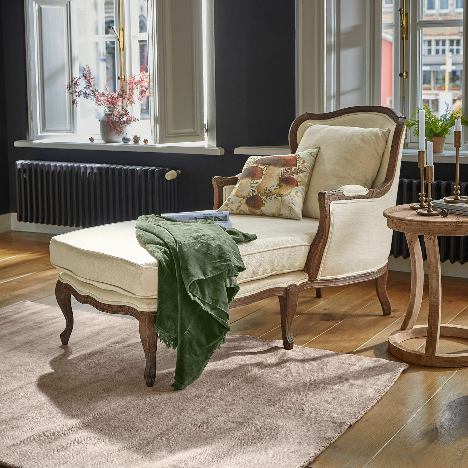 Chaise-longue Muel Chaise longue beige con struttura in legno e coperta verde in soggiorno luminoso con pavimento in legno