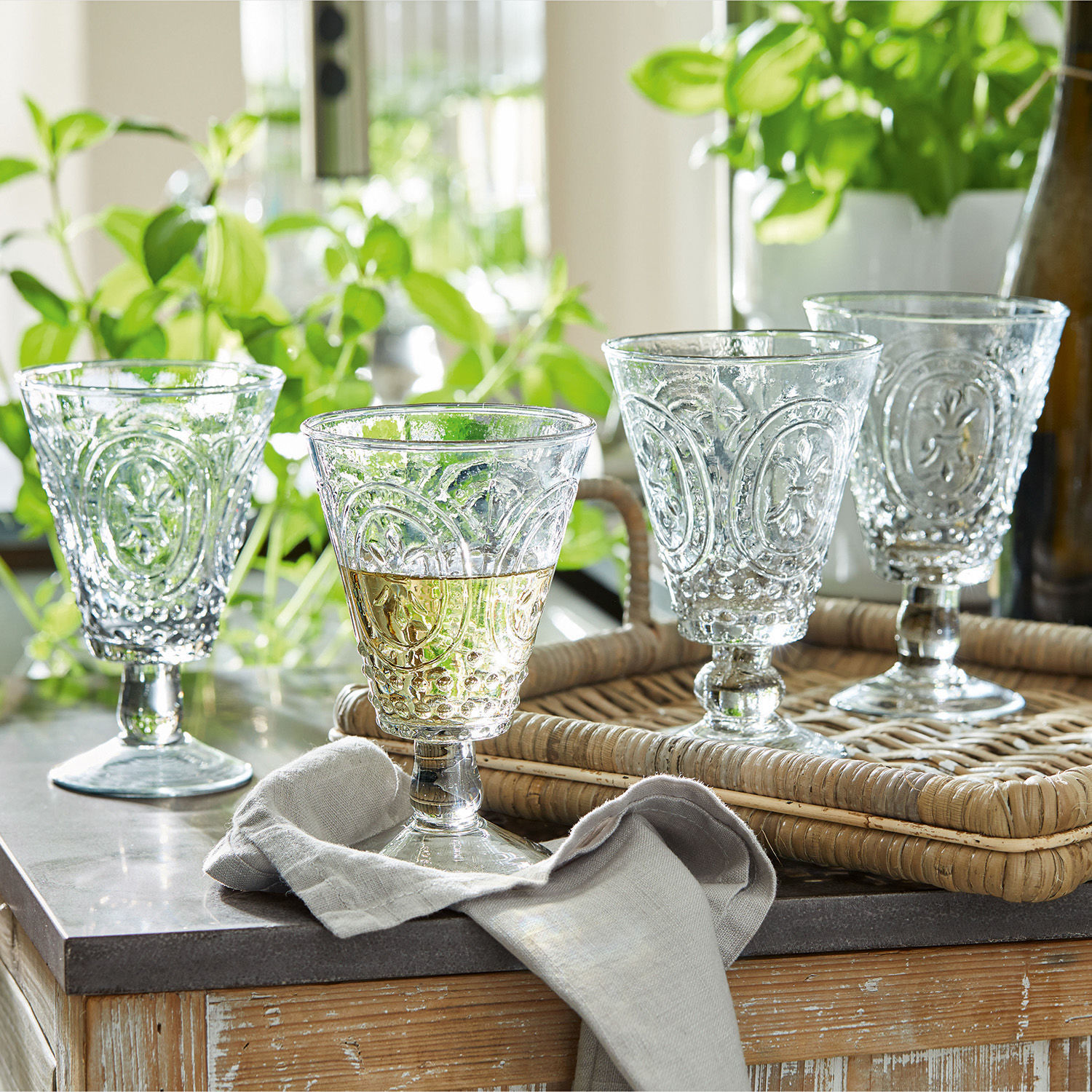 Set di 4 bicchieri da vino Sarton Set di quattro bicchieri trasparenti con motivo decorativo su vassoio in rattan su tavolo