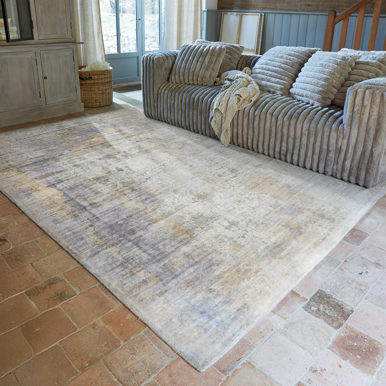 Tappeto Qalheera Grande tappeto beige e grigio su pavimento in mattoni in soggiorno accogliente con divano grigio