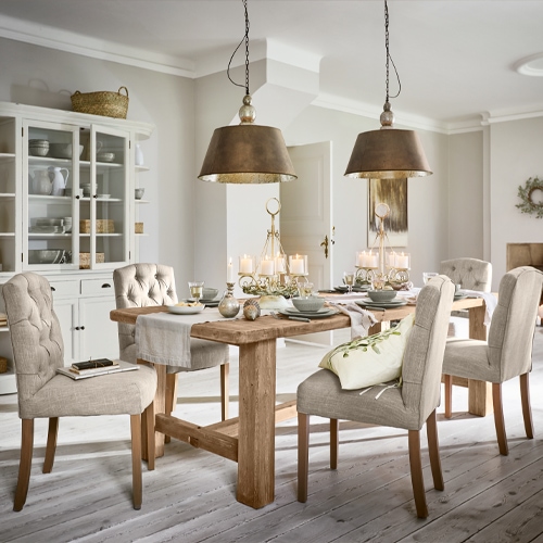 Sala da pranzo con tavolo in legno massiccio e sedie imbottite beige, lampade a sospensione in metallo